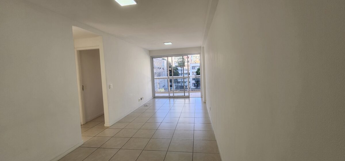 Sala com varanda ao fundo e piso de porcelanato